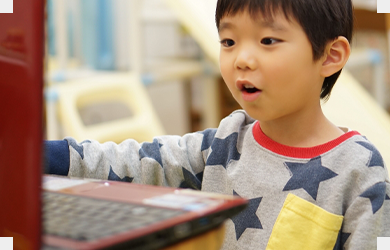 ノートパソコンに向かってプログラミングをする男の子