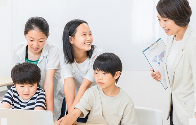 メンターが子どもたちのパソコンをのぞき込んで教えている様子