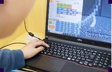 ノートパソコンでスクラッチのブロックを操作する子ども
